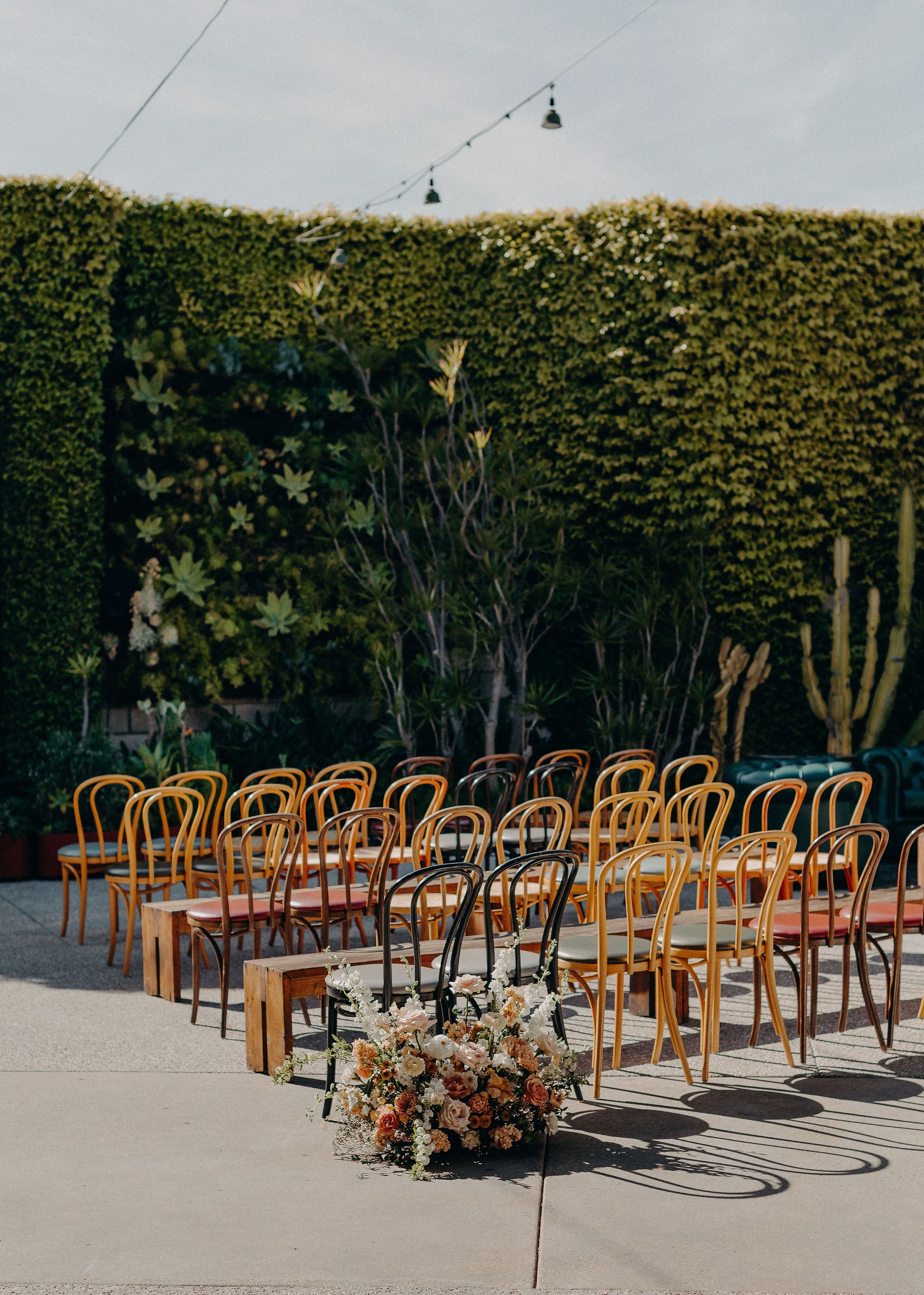 Wooden ceremony chairs and flowers in SmogShoppe’s planted courtyard